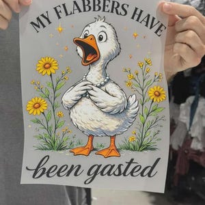 K&ouml;nnte beinhalten: Ein rechteckiger Druck mit einer wei&szlig;en Ente mit orangefarbenem Schnabel und F&uuml;&szlig;en, die eine Perlenkette tr&auml;gt. Die Ente ist von gelben Blumen und Sternchen umgeben. Der Text lautet oben MY FLABBERS HAVE und unten been gasted.