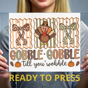 May include: A rectangular sign featuring three vertical panels with scalloped edges. The left and right panels show polka-dot bows, while the center panel displays a turkey wearing a hat. Text reads GOBBLE + GOBBLE Till you wobble with pumpkins.