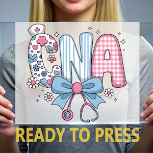 May include: A decorative CNA design with a nurse's hat, hearts, flowers, and a stethoscope. The letters are in blue and pink, with the text "READY TO PRESS" in yellow at the bottom. The design is on a clear background.