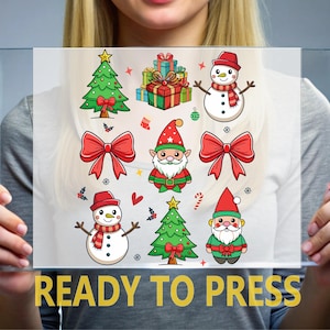 May include: A collection of Christmas-themed graphics, including a Christmas tree, snowman, gift boxes, bows, and gnomes. The phrase "READY TO PRESS" is printed in yellow at the bottom of the image. The graphics are colorful and cartoon-like.