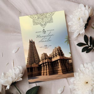 May include: A wedding invitation with a temple illustration and the text "Maavilan weds Amala" with the date "06 July 2025". The invitation has a decorative border and is set against a soft, neutral background with white flowers.