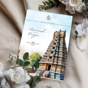May include: A wedding invitation featuring a watercolor illustration of a temple with a multi-tiered structure. The invitation includes the names "Avinash Weds Divya" and the date "06 July 2025". The background is a soft blue with floral accents.