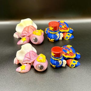 Peut inclure: Ensemble de figurines fantaisistes et colorées. L'ensemble comprend des figurines roses en forme d'œil avec des couronnes et des figurines bleues et rouges en forme de soldats. Les détails sont mis en valeur par des accents jaunes et blancs, créant une esthétique ludique et imaginative.