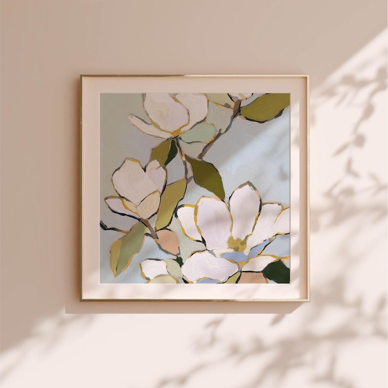 Puede incluir: Impresi&oacute;n art&iacute;stica enmarcada que presenta grandes flores de magnolia blancas con detalles dorados y hojas verdes sobre un fondo azul claro. La obra de arte se muestra en un marco dorado, creando una est&eacute;tica serena y elegante.