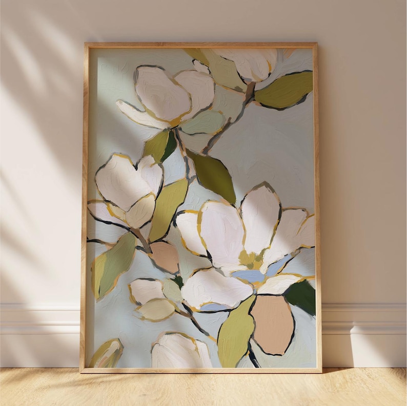 Puede incluir: Impresi&oacute;n art&iacute;stica enmarcada que presenta grandes flores de magnolia blancas con detalles amarillos y rosas, sobre un fondo azul claro. La pintura incluye hojas verdes y tallos marrones, todo dentro de un marco de madera natural.