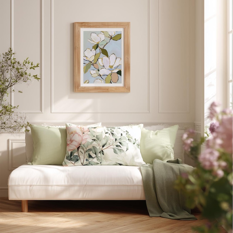 Puede incluir: Un sof&aacute; de color claro con cojines verdes y un coj&iacute;n con estampado floral. Una pintura floral enmarcada cuelga sobre el sof&aacute;. Una manta verde est&aacute; sobre el sof&aacute;. La habitaci&oacute;n tiene un ambiente ligero y aireado.