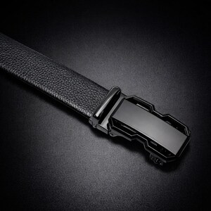 Peut inclure: Gros plan d'une ceinture en cuir noir avec une surface texturée. La ceinture est dotée d'une boucle noire rectangulaire et élégante. L'image est prise sur un fond sombre, mettant en valeur les détails de la ceinture.