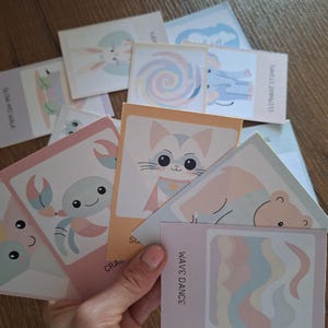 May include: A set of colorful illustrated cards featuring various animals and designs. The cards include a crab, a cat, a wave, a turtle, a bunny, a lollipop, an elephant, and a bear. The cards are perfect for a variety of craft projects, including scrapbooking, card making, and journaling.