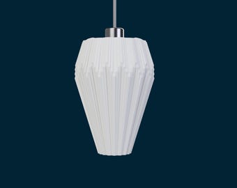 May include: White pendant light fixture with a geometric, textured shade. The shade has a cone-like shape with vertical lines and a silver-colored metal top. The light hangs from a thin, silver-colored wire against a dark blue background.