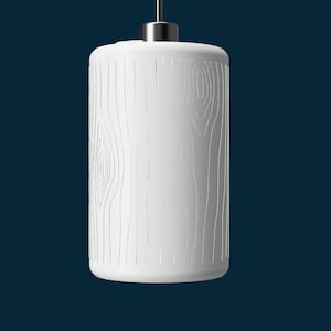 May include: A white, cylindrical pendant light with a wood grain design. The light hangs from a silver cap and cord against a dark blue backdrop. The fixture is approximately 25 cm tall.