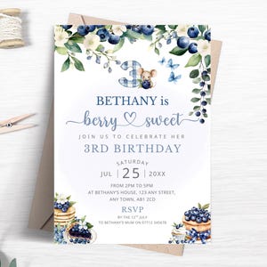 May include: A rectangular birthday invitation card featuring watercolor illustrations of blueberries, green leaves, white flowers, and a small mouse. The text reads BETHANY is berry sweet JOIN US TO CELEBRATE HER 3RD BIRTHDAY SATURDAY JUL 25 20XX.
