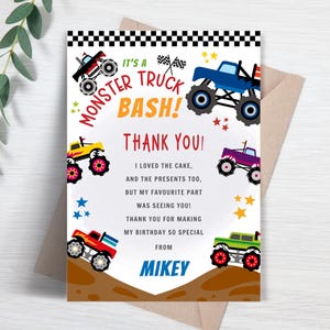 May include: A colorful "Monster Truck Bash" thank you card. The card features illustrations of monster trucks in various colors, stars, and the text "Thank You!" The card is on a white background with a brown envelope.