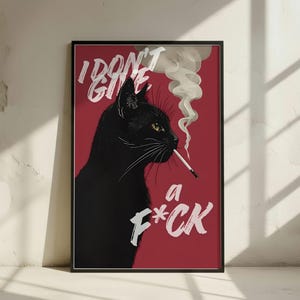 Op de afbeelding: Ingelijste kunstprint met een zwarte kat die een sigaret rookt, tegen een rode achtergrond. De witte tekst luidt "I DON'T GIVE a F*CK". De kat heeft gele ogen en rookt een sigaret.