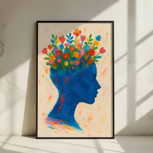 Può includere: Una stampa artistica incorniciata raffigurante una silhouette blu di una testa con fiori colorati che sbocciano dalla sommità. L'opera d'arte ha un aspetto strutturato e dipinto, su uno sfondo color crema, all'interno di una cornice nera. I fiori sono nelle tonalità di rosso, arancione, giallo e blu.