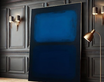 May include: Abstract painting with two horizontal bands of blue paint. The top band is a lighter shade of blue and the bottom band is a darker shade of blue. The painting is framed in a thin gold frame and is hanging on a dark wall.