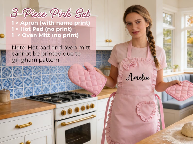 Pode incluir: Um conjunto de cozinha rosa de 3 pe&ccedil;as, incluindo um avental com o nome "Amelia", um pegador e uma luva de forno. O avental tem um la&ccedil;o e um bolso em forma de cora&ccedil;&atilde;o. O pegador e a luva t&ecirc;m um padr&atilde;o acolchoado.