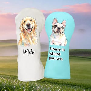 Könnte beinhalten: Zwei Golfschlägerhauben. Eine ist weiß mit einem Aquarellbild eines Golden Retrievers und dem Namen "Milo". Die andere ist hellblau mit einer Französischen Bulldogge und dem Text "Home is where you are."