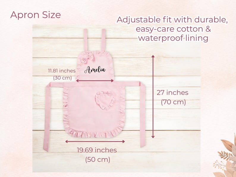 Pode incluir: Um avental rosa com borda franzida, la&ccedil;o e bolso em forma de cora&ccedil;&atilde;o. O avental tem 50 cm de largura, 70 cm de comprimento e uma largura superior de 30 cm. O avental tem o nome "Amelia" impresso.