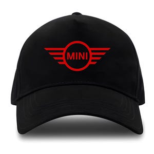 Pode incluir: Boné de beisebol preto com o logotipo MINI vermelho. O logotipo apresenta a palavra "MINI" dentro de um círculo vermelho, ladeada por elementos vermelhos em forma de asas. O boné tem uma viseira curva e é projetado para uso casual.