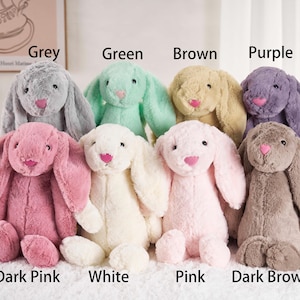 May include: A collection of plush bunny rabbits in various colors, including grey, green, brown, purple, dark pink, white, pink, and dark brown. Each bunny has long floppy ears, a pink nose, and a soft, cuddly appearance. The image includes text labels for each color.