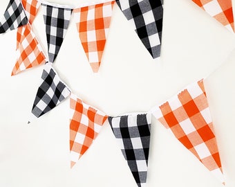 May include: A black and orange checkered bunting with alternating flags. The flags are triangular and have a white backing.