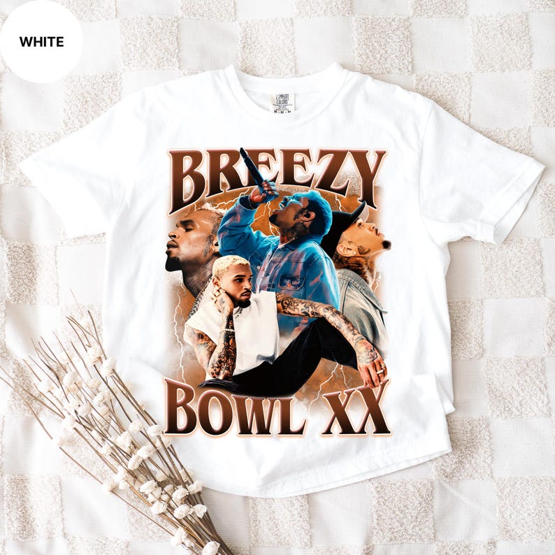 Puede incluir: Camiseta blanca con un dise&ntilde;o gr&aacute;fico marr&oacute;n que dice "BREEZY BOWL XX". El dise&ntilde;o incluye m&uacute;ltiples im&aacute;genes de una persona tatuada, con una camisa azul y sosteniendo un micr&oacute;fono.