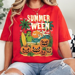 May include: Red t-shirt with a graphic design featuring the text "SUMMER WEEN". The design includes palm trees, a Frankenstein monster with a surfboard, ghosts, pumpkins, and a pineapple with a jack-o'-lantern face. The shirt is a casual wear item.