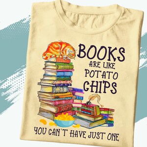 May include: A yellow t-shirt with a graphic of a cat sleeping on a stack of books. The text on the shirt reads "Books are like potato chips you can't have just one".