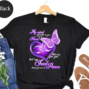May include: Black t-shirt featuring a purple butterfly and heart design with the text "My mind still talks to you and my heart but my soul peace knows you are at". The shirt is made of a soft material.