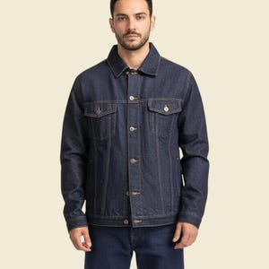 May include: A dark blue denim jacket with a button-up front, two chest pockets, and two side pockets. The jacket has a classic collar and is worn with matching blue jeans. The jacket is a standard fit.