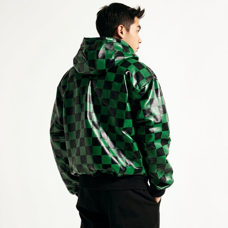 Puede incluir: Una chaqueta con capucha con un patr&oacute;n de tablero de ajedrez negro y verde. La chaqueta tiene un dobladillo y pu&ntilde;os de canal&eacute; negros. El material parece ser brillante, posiblemente polipiel. La chaqueta se lleva sobre pantalones negros.