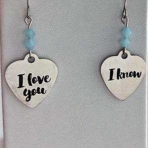 May include: A pair of silver heart-shaped earrings with blue crystal accents. The left earring says "I love you" and the right earring says "I know".