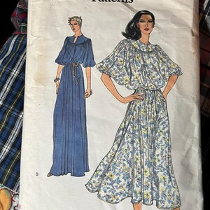 May include: A Very Easy Vogue Patterns sewing pattern envelope, number 7128, size 12. The front displays illustrations of two dress styles: one solid blue floor-length dress and one midi-length dress with a blue and yellow floral print.
