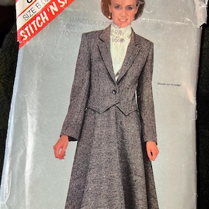 May include: A vintage sewing pattern package featuring a woman in a gray tweed skirt suit. The package has a red and white sticker that reads "STITCH 'N SAVE". The pattern is size B (12-14-16).