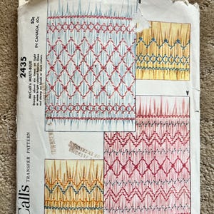 May include: Vintage McCall's transfer pattern 2435, featuring smocking designs in red, blue, and yellow. The pattern includes text indicating it stamps on light or bright fabrics and is adaptable to different depths. The price is 50c.