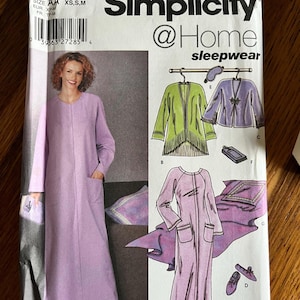 May include: A Simplicity @Home sleepwear sewing pattern envelope, number 5264, for sizes XS, S, and M. The front displays a lavender robe, a green cardigan, a purple jacket, a sleep mask, slippers, and a pillowcase with illustrations and text.