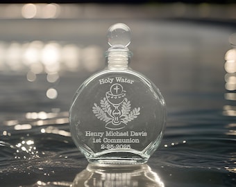 Puede incluir: Una botella de vidrio transparente con cuerpo redondo y tapón de vidrio. La botella está grabada con las palabras "Holy Water", un diseño de cáliz y trigo, y el nombre "Henry Michael Davis", "1st Communion" y la fecha "2-25-2025".