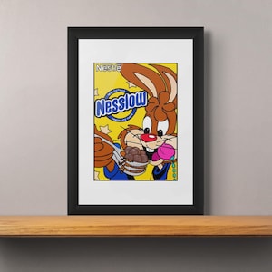 Puede incluir: Una impresión enmarcada de un conejo de dibujos animados comiendo cereales. El conejo es marrón y blanco con la nariz rosa. La caja de cereales es amarilla con texto azul y blanco que dice "Nestle Nesquik".