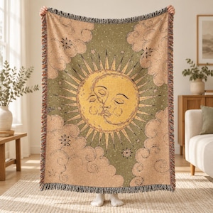 Peut inclure: Un plaid tissé présentant un motif central de soleil et de lune aux visages aux yeux fermés. Le fond est vert olive avec des étoiles éparpillées, entouré de nuages beiges et d'un bord à franges. Le soleil a des rayons rayonnants.