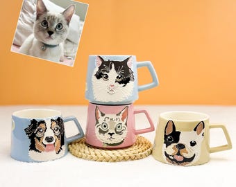 May include: Four ceramic mugs with animal faces: a black and white cat, a pink cat, a dog, and a bulldog. Each mug has a different color and handle. A photo of a cat is in the upper left corner.