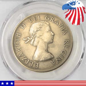 Puede incluir: Una moneda dorada que presenta el perfil de una mujer con una corona de laurel, rodeada de texto. La moneda está dentro de un soporte de plástico transparente. El texto de la moneda incluye "ELIZABETH II DEI GRATIA REGINA".