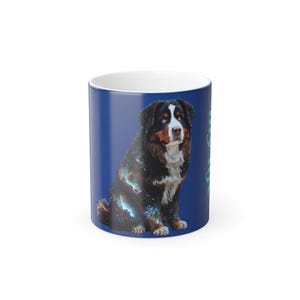 Puede incluir: Una taza de cerámica azul con interior blanco presenta un perro de montaña bernés con un patrón de galaxia. El perro está sentado y mirando hacia la derecha.