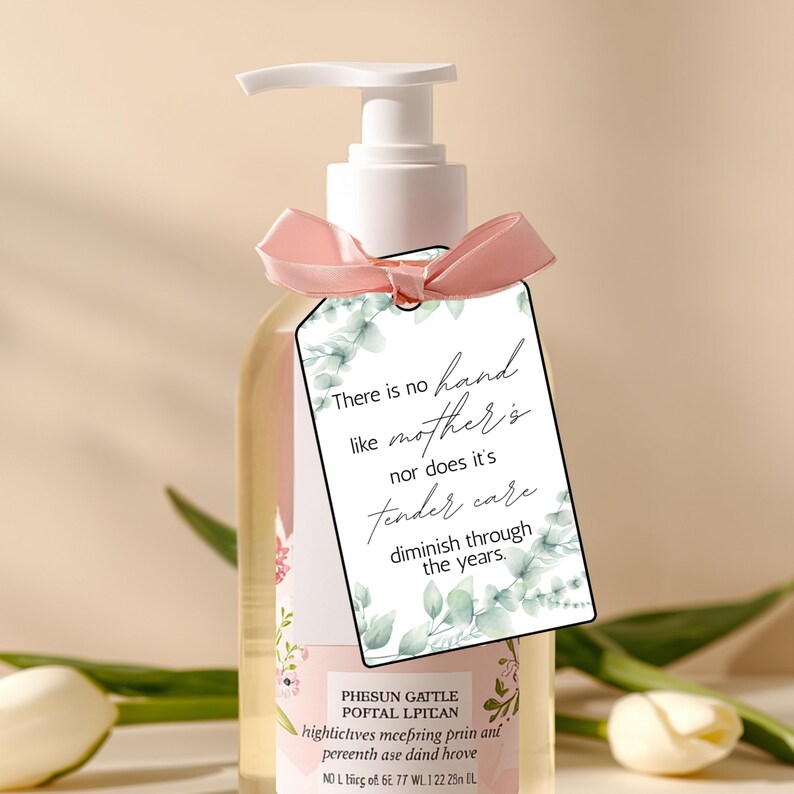 May include: A clear liquid soap bottle with a white pump and a pink ribbon. A gift tag with a floral design and the text "There is no hand like mother's" is attached. The bottle has a floral design. The soap is likely measured in milliliters.