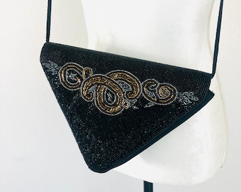 May include: A black beaded evening bag with a gold and silver beaded design. The bag has a long strap.