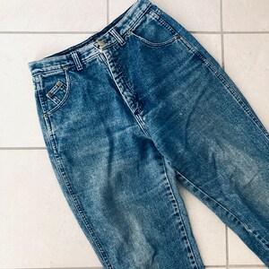 Op de afbeelding: Een paar blauwe denim jeans met een distressed look. De jeans heeft een hoge taille en een rechte pijp.