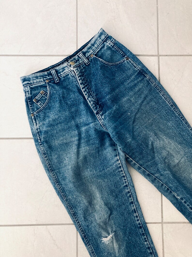 Op de afbeelding: Een paar blauwe denim jeans met een distressed look. De jeans heeft een hoge taille en een rechte pijp.