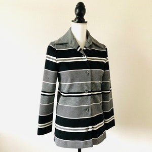 May include: A black, white, and gray striped button-up jacket with a collar.