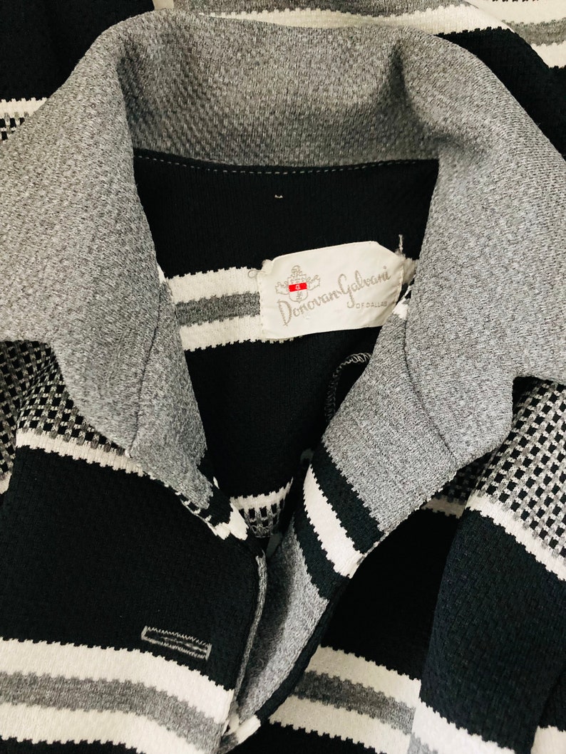 May include: Black and white striped shirt with a gray collar and a label that reads "Donovan Galvani" in white text.