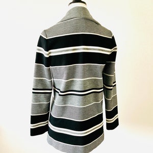 May include: A black and white striped blazer with a textured pattern. The blazer has a collar and long sleeves.