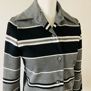 May include: A black and gray striped long-sleeved shirt with a button-up front and a collar.